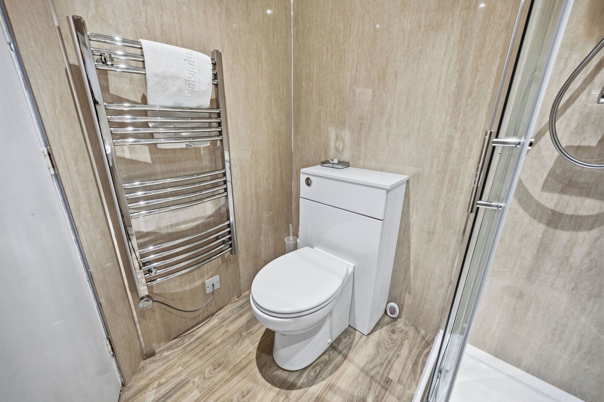 Een moderne badkamer met toilet, handdoekhouder en douche.