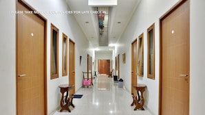 A hotel hallway with wooden doors, a central walkway, and a ceiling with recessed lighting. - Casa Vanda Guesthouse (South Tangerang)