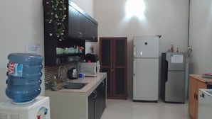 A compact kitchen with a refrigerator, a microwave, and a water dispenser. - Casa Vanda Guesthouse (South Tangerang)