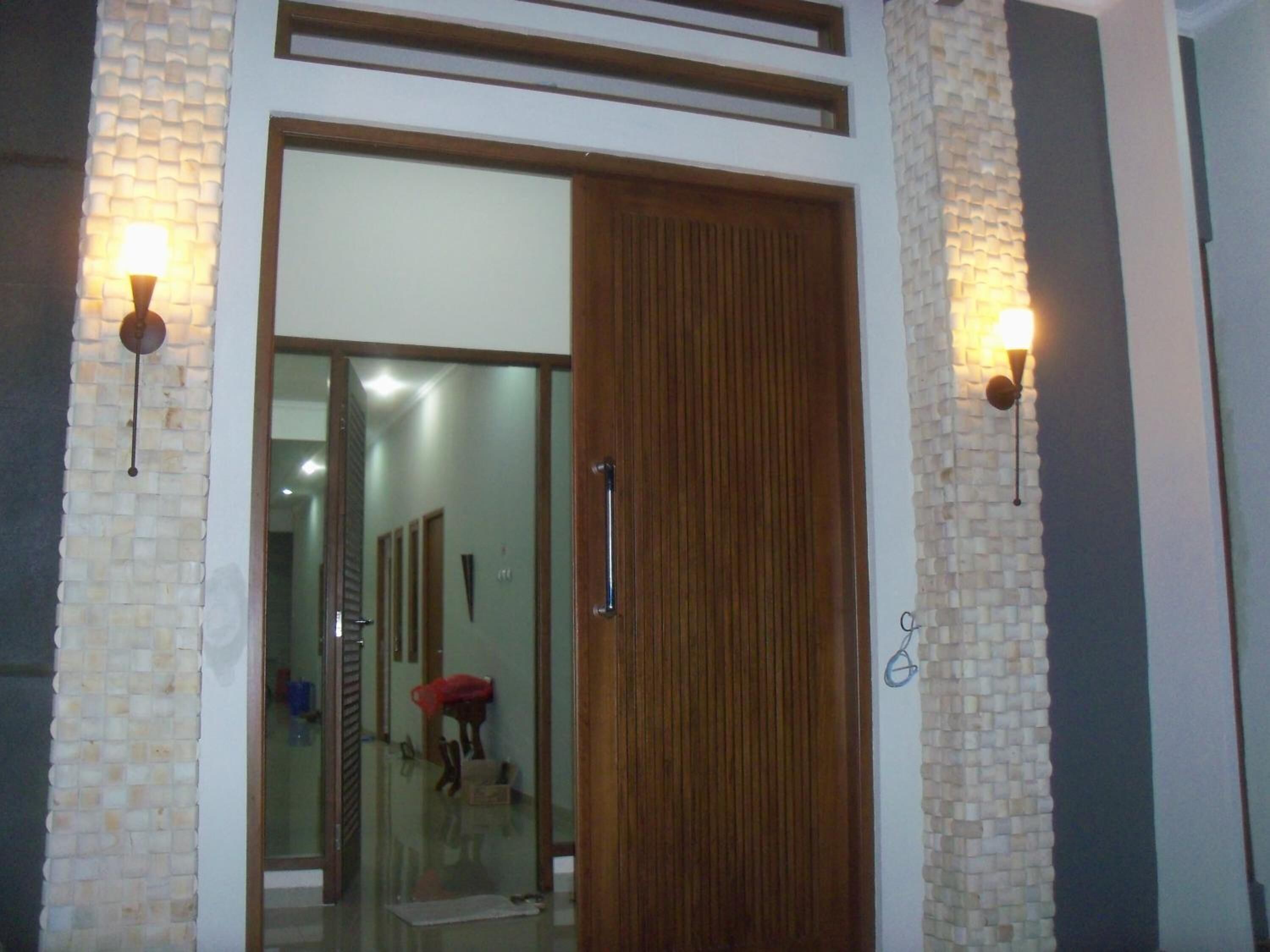A modern interior with a wooden door, glass panels, and two wall-mounted lights.