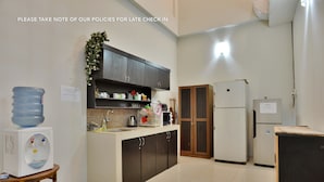 A kitchen with a water dispenser, cabinets, a microwave, and a refrigerator. - Casa Vanda Guesthouse (South Tangerang)