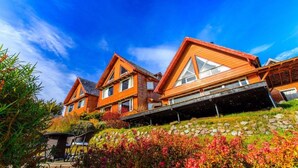 Une rangée de maisons en bois, dotées de grandes fenêtres, et un chemin de pierre menant à un espace aménagé pour s’asseoir.
