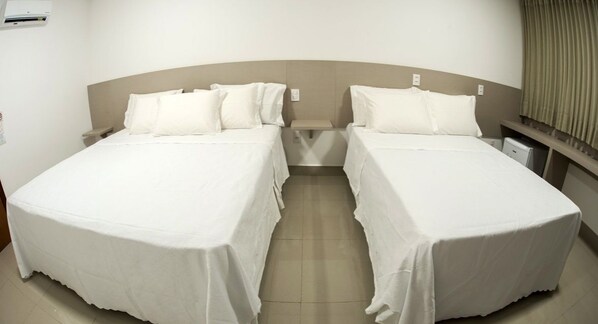 A hotel room with two single beds, a bedside table, a nightstand, and a window with curtains. - Liguori Hotel (Trindade)
