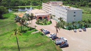 A hotel with a central courtyard, surrounded by lush greenery and a body of water. - Liguori Hotel (Trindade)