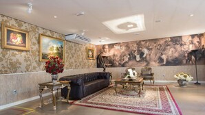 A spacious living room with a large mural, a leather sofa, a coffee table, and a patterned rug. - Liguori Hotel (Trindade)