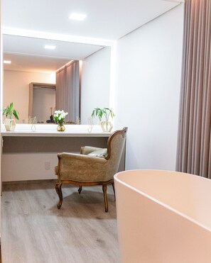 A modern bathroom with a vanity, a chair, and a large mirror. - Liguori Hotel (Trindade)