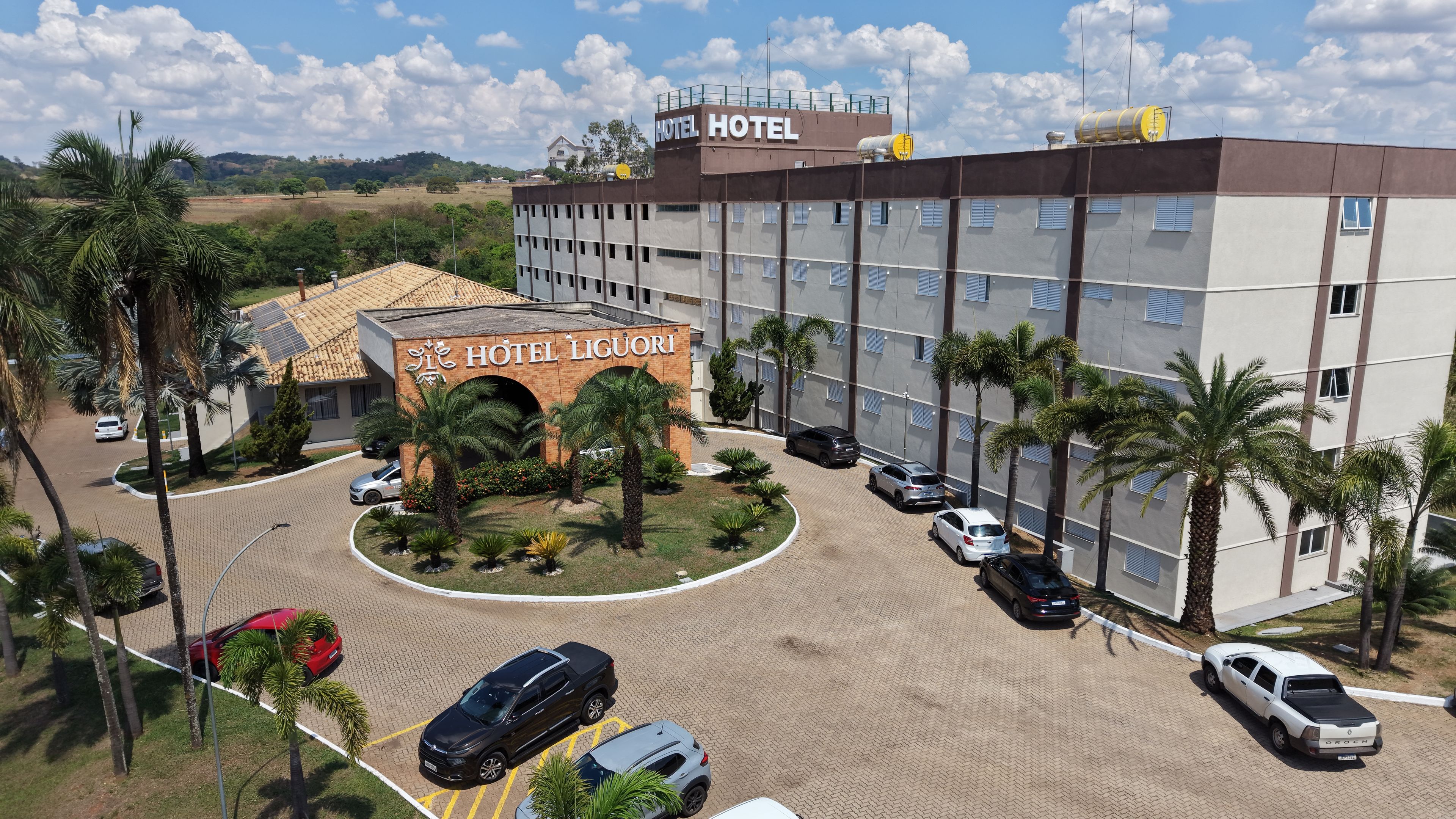 A hotel with a prominent entrance, multiple parking spaces, and a landscaped area with palm trees.