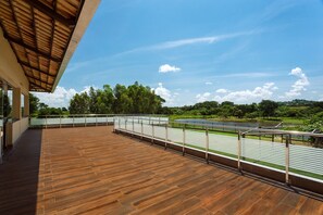 A wooden deck with a metal railing overlooking a river and greenery. - Liguori Hotel (Trindade)
