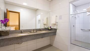 A modern bathroom with two sinks, a glass shower enclosure, and a large mirror.