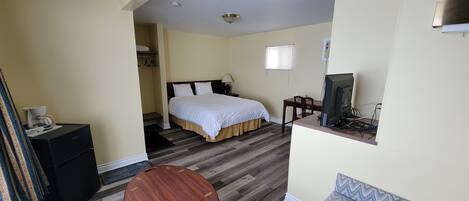 A hotel room with a bed, a desk with a computer, a small table, and a wardrobe.