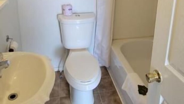 A bathroom with a toilet, sink, and bathtub. - North Shore Wayside Inn (Blind River)