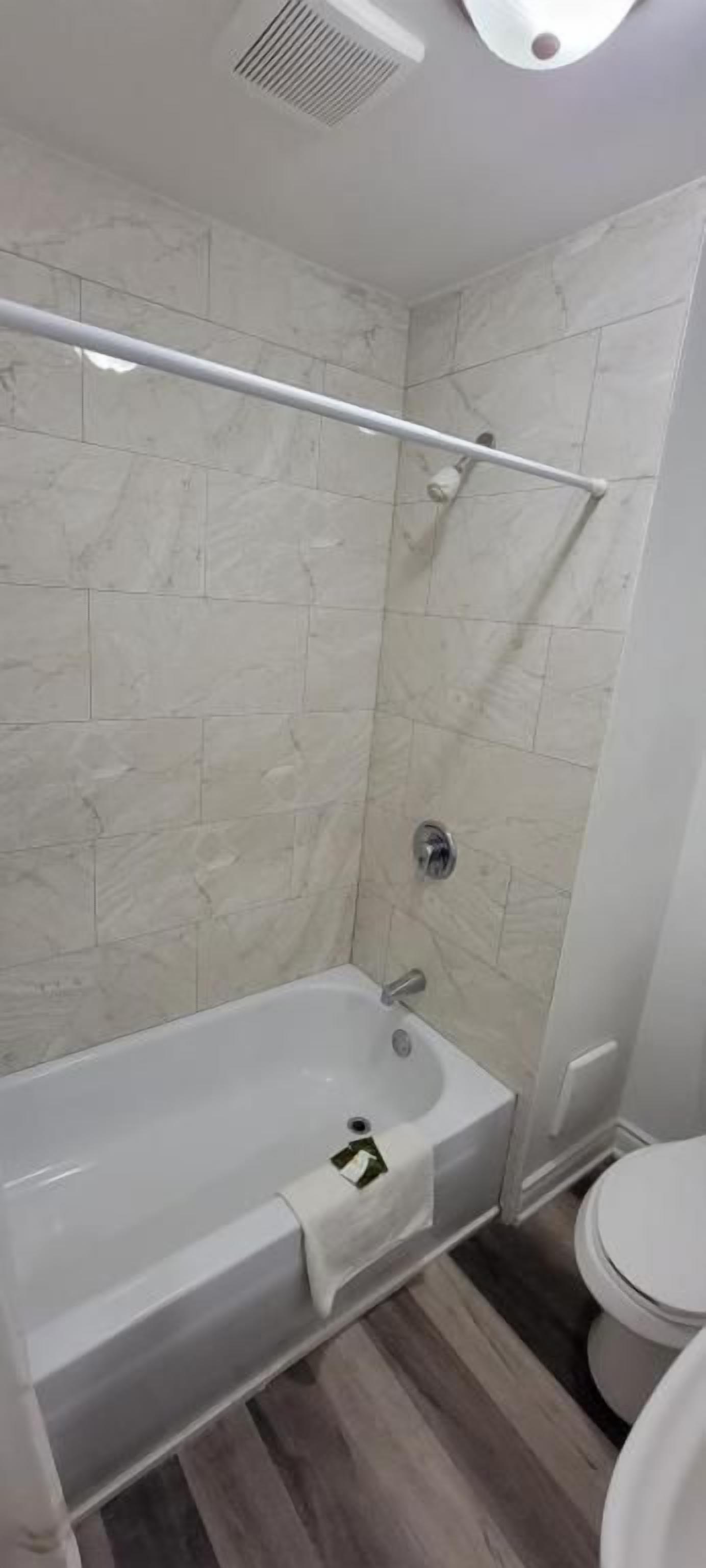 Een badkamer met een bad, douche en toilet.