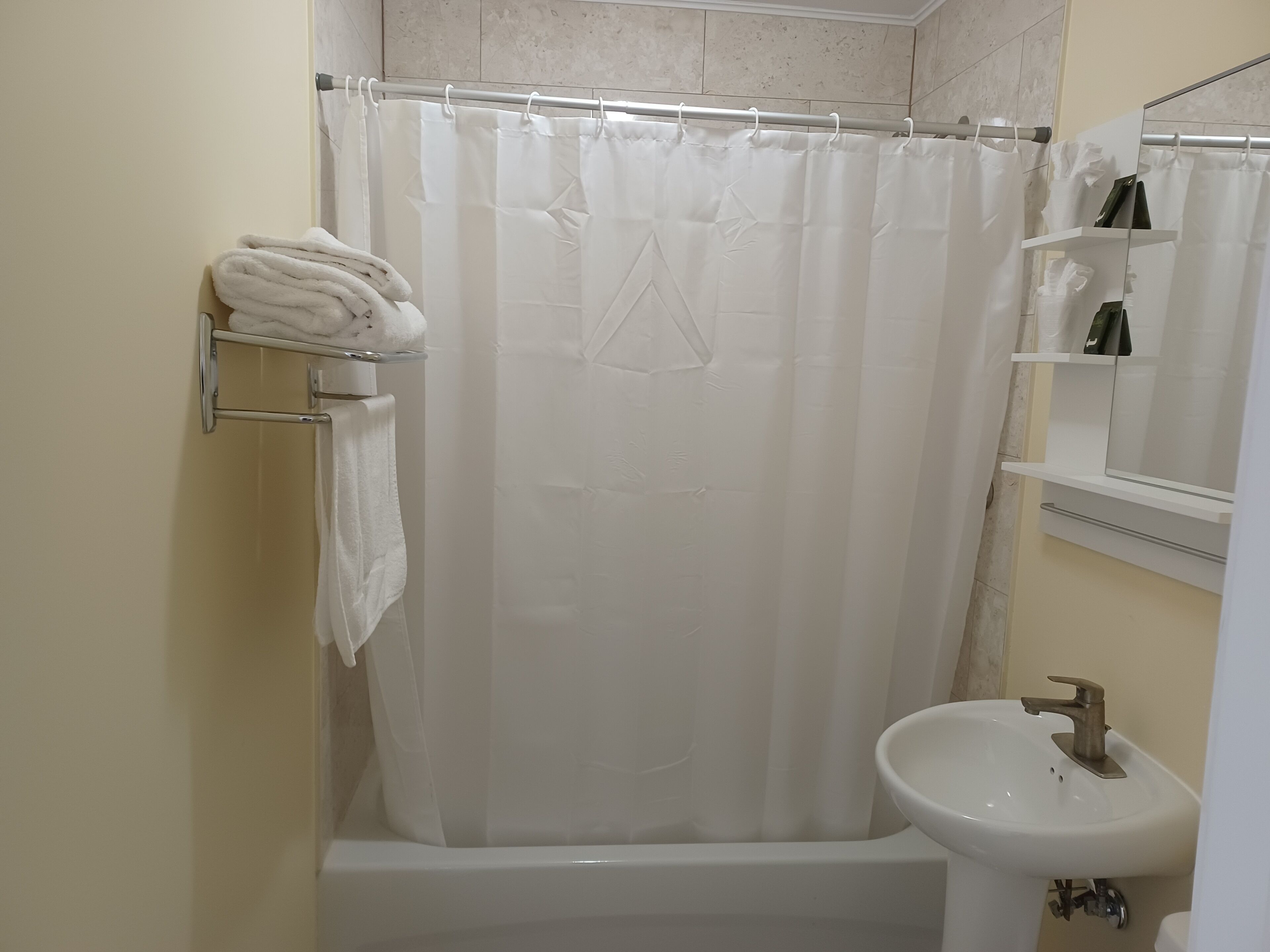 A bathroom with a bathtub, a white sink, and a shower curtain.