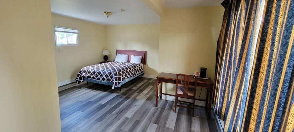 A bedroom with a bed, a desk, a chair, a lamp, and a window.