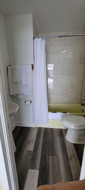 A bathroom with a toilet, sink, and bathtub. - North Shore Wayside Inn (Blind River)