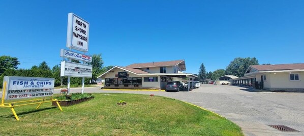 A motel with a signboard, a parking area, and a roadside eatery.
