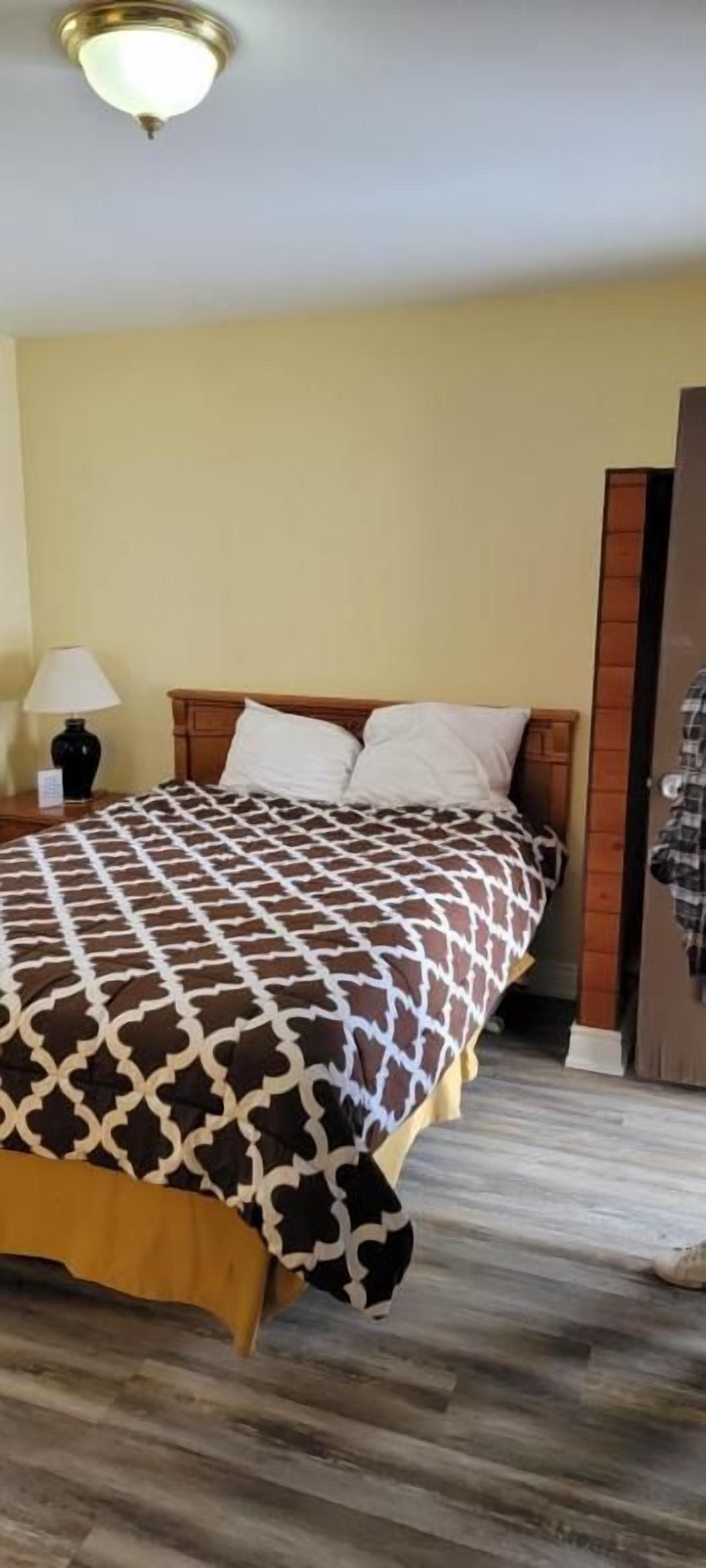 A bed with a patterned bedspread, a bedside lamp, and a wooden headboard.