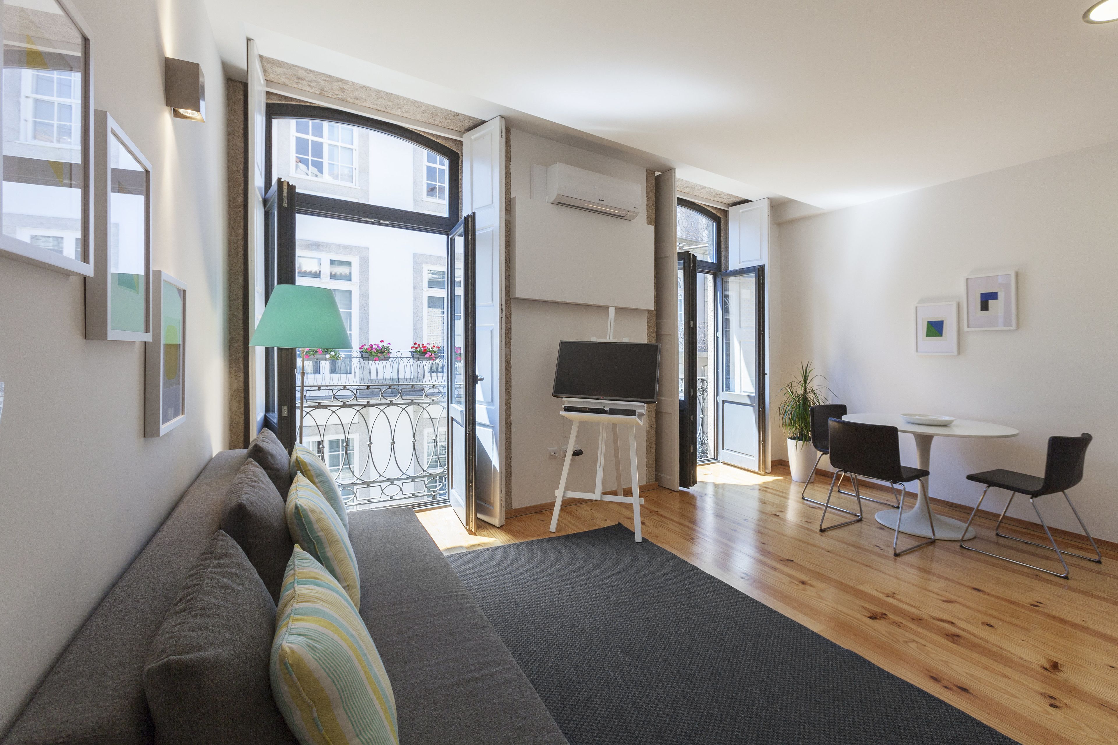 Ein modernes Wohnzimmer mit einer Couch, einem Schreibtisch mit Computer und einem Essbereich mit Stühlen.