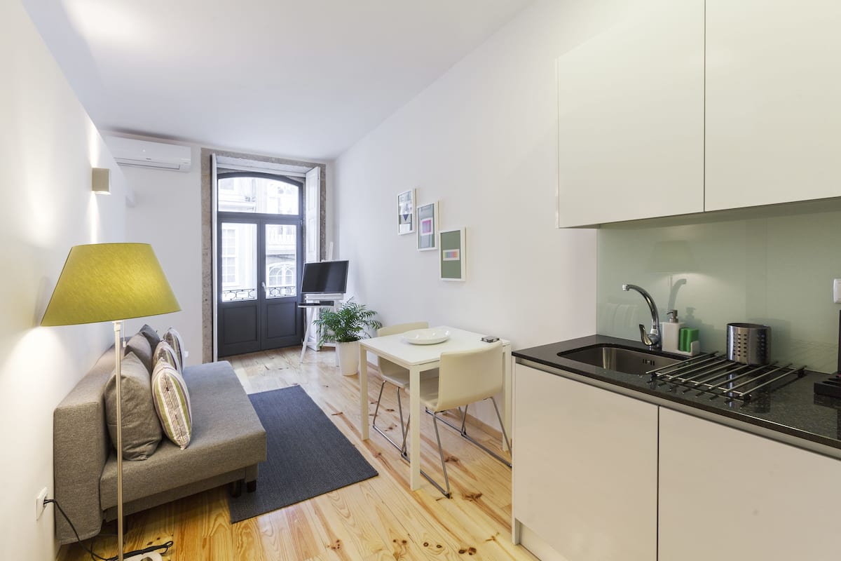 A compact living space with a kitchenette, a dining area, and a sofa with a lamp.