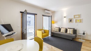A modern living room with a sofa, yellow armchair, and a dining table with a white plate. - BO - Almada 340 (Porto)