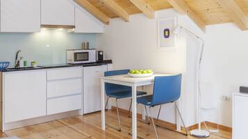 Une cuisine moderne avec des meubles blancs, un four à micro-ondes et une table à manger entourée de chaises bleues.