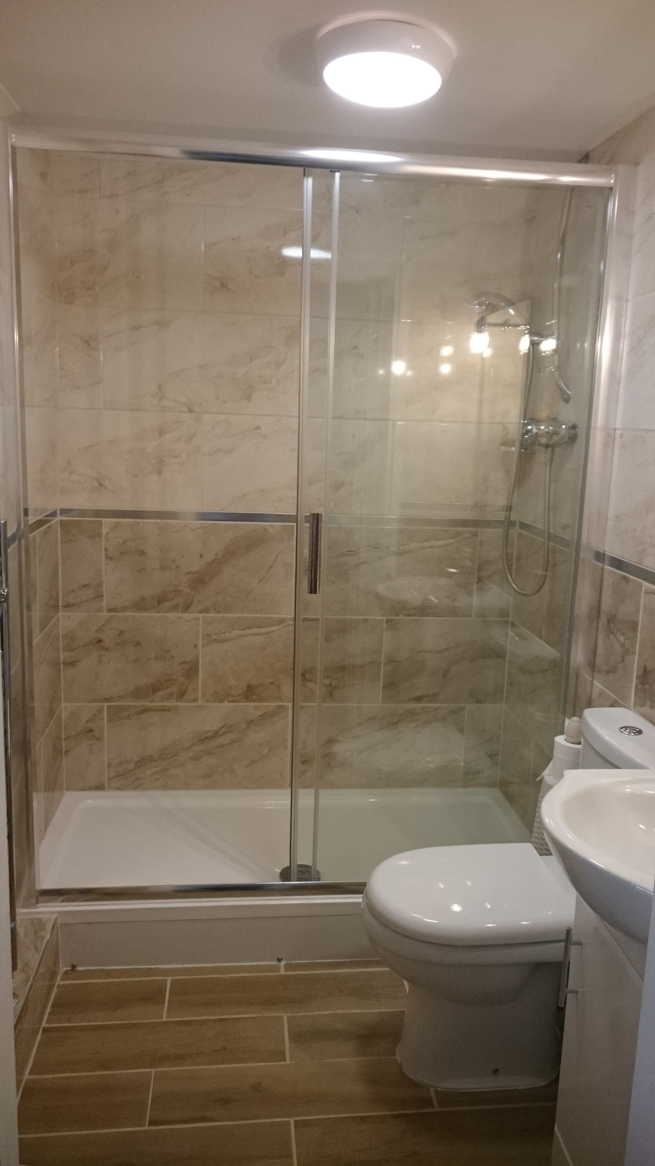 A bathroom with a glass-enclosed shower, a toilet, and a sink.