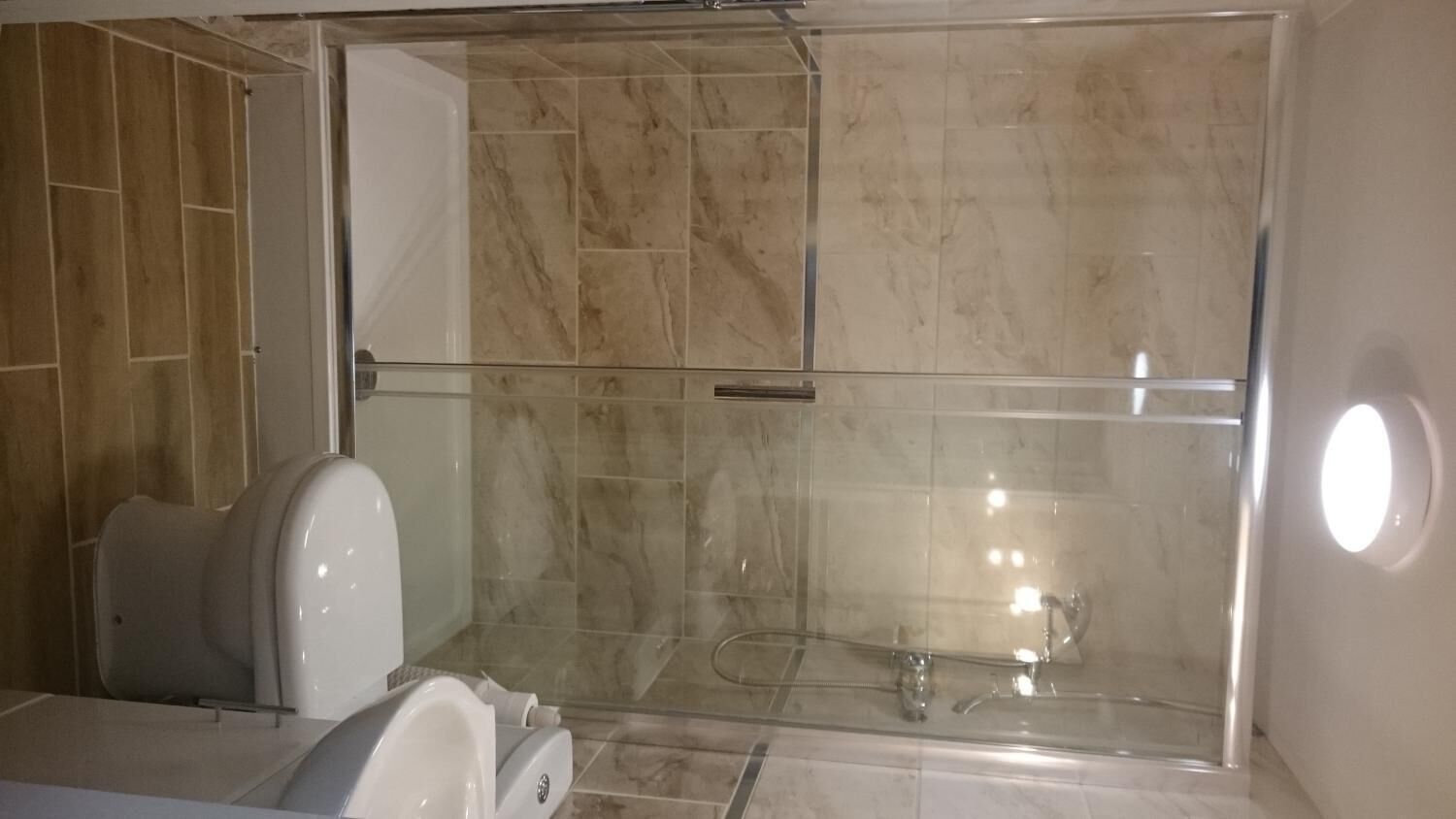 Ein modernes Badezimmer mit Duschkabine aus Glas, Toilette und Waschbecken.