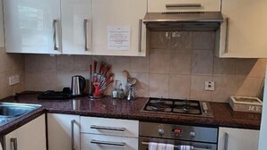 Een moderne keuken met witte kasten, een roestvrijstalen fornuis en een inbouwoven.