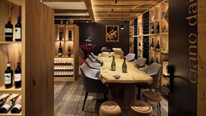 A wooden interior with a bar area, wine racks, and seating. - Hotel Savoy (Badia)