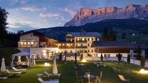 A hotel with a large outdoor area featuring sun loungers, a tent, and tables. - Hotel Savoy (Badia)
