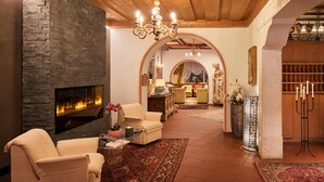 A cozy living room with a stone fireplace, comfortable seating, and a chandelier. - Hotel Savoy (Badia)