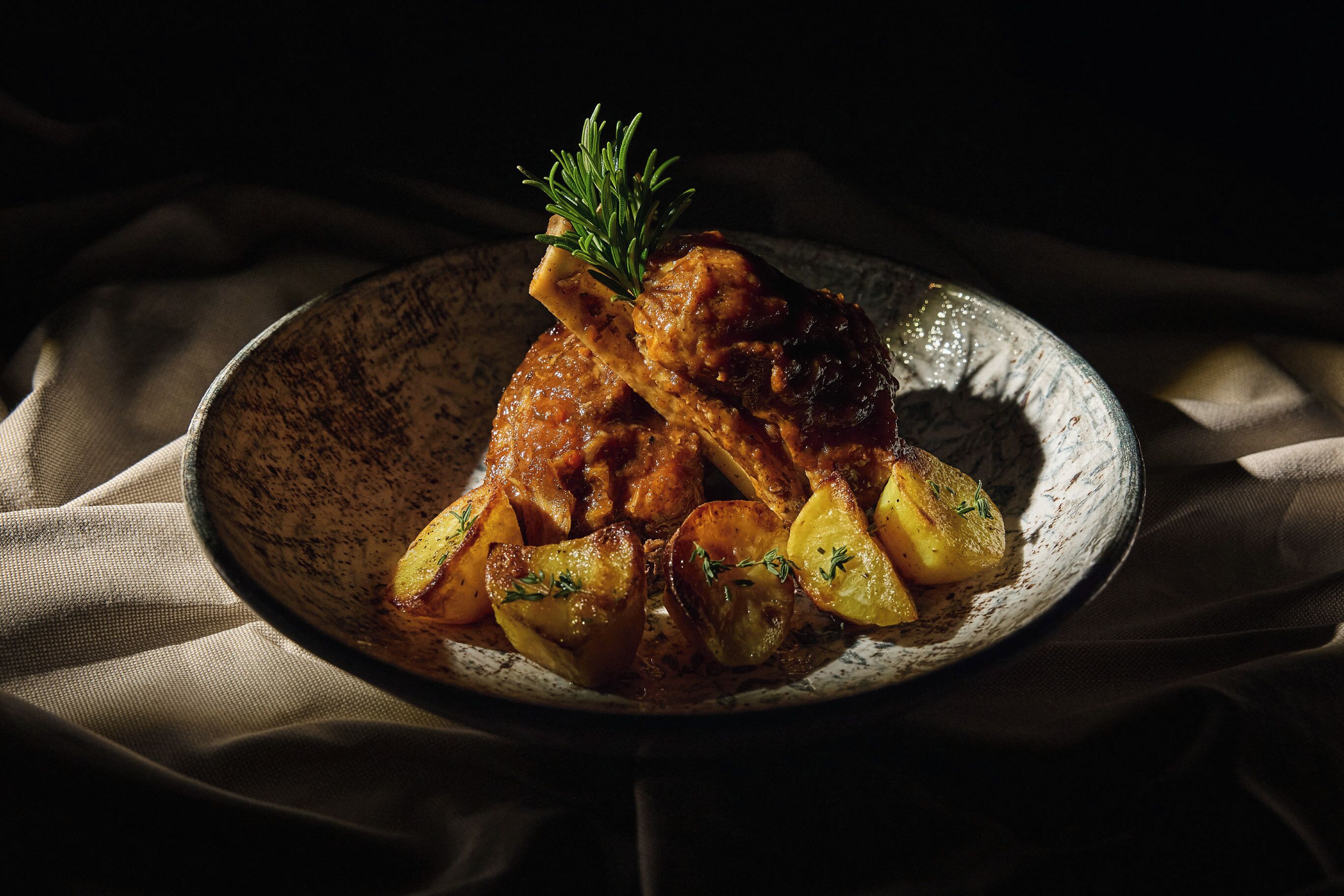 Un piatto di pollo arrosto e patate guarnito con erbe aromatiche.