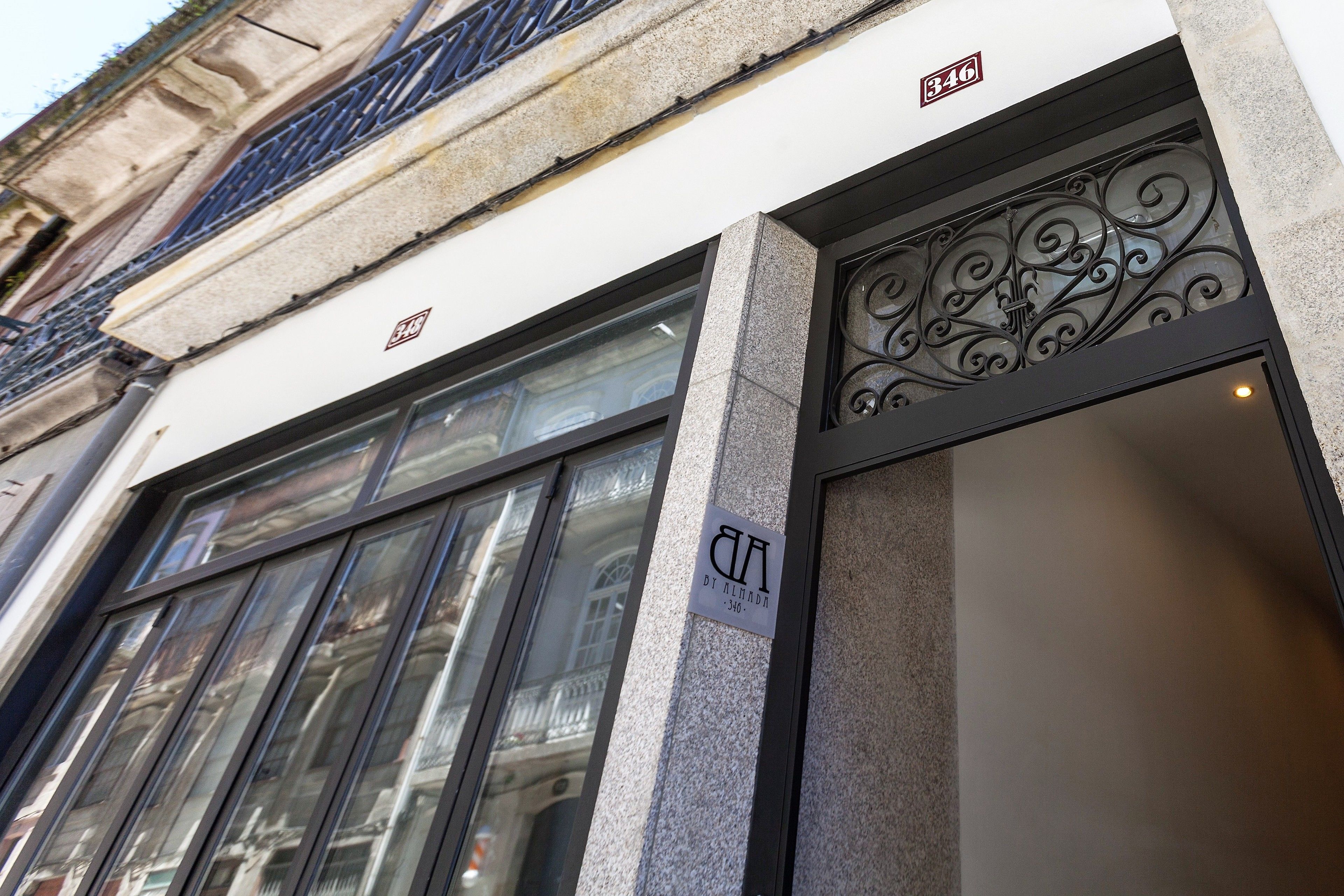 Fachada de edifício com grandes janelas, um letreiro com 'AIA' e '346', e uma entrada em ferro ornamental.