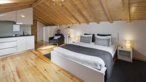 Un dormitorio moderno con una cama grande, mesitas de noche, ventilador de techo y una zona de cocina con armarios y encimera.