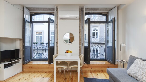 Un apartamento moderno con piso de madera, una mesa de comedor con sillas, un televisor y un sofá.