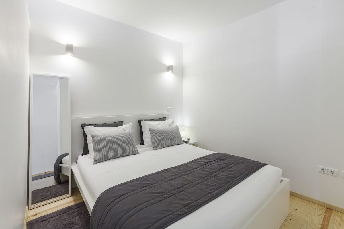 Un dormitorio moderno con una cama grande, dos mesitas de noche y un espejo.