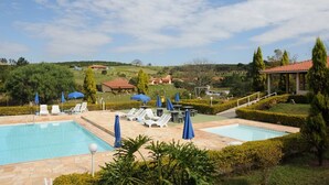 A pool area with two pools, lounge chairs, and umbrellas. - Hotel Fazenda Santa Maria (Serra Negra)