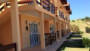 A multi-story hotel with balconies, a covered outdoor seating area, and a landscaped garden. - Hotel Fazenda Santa Maria (Serra Negra)