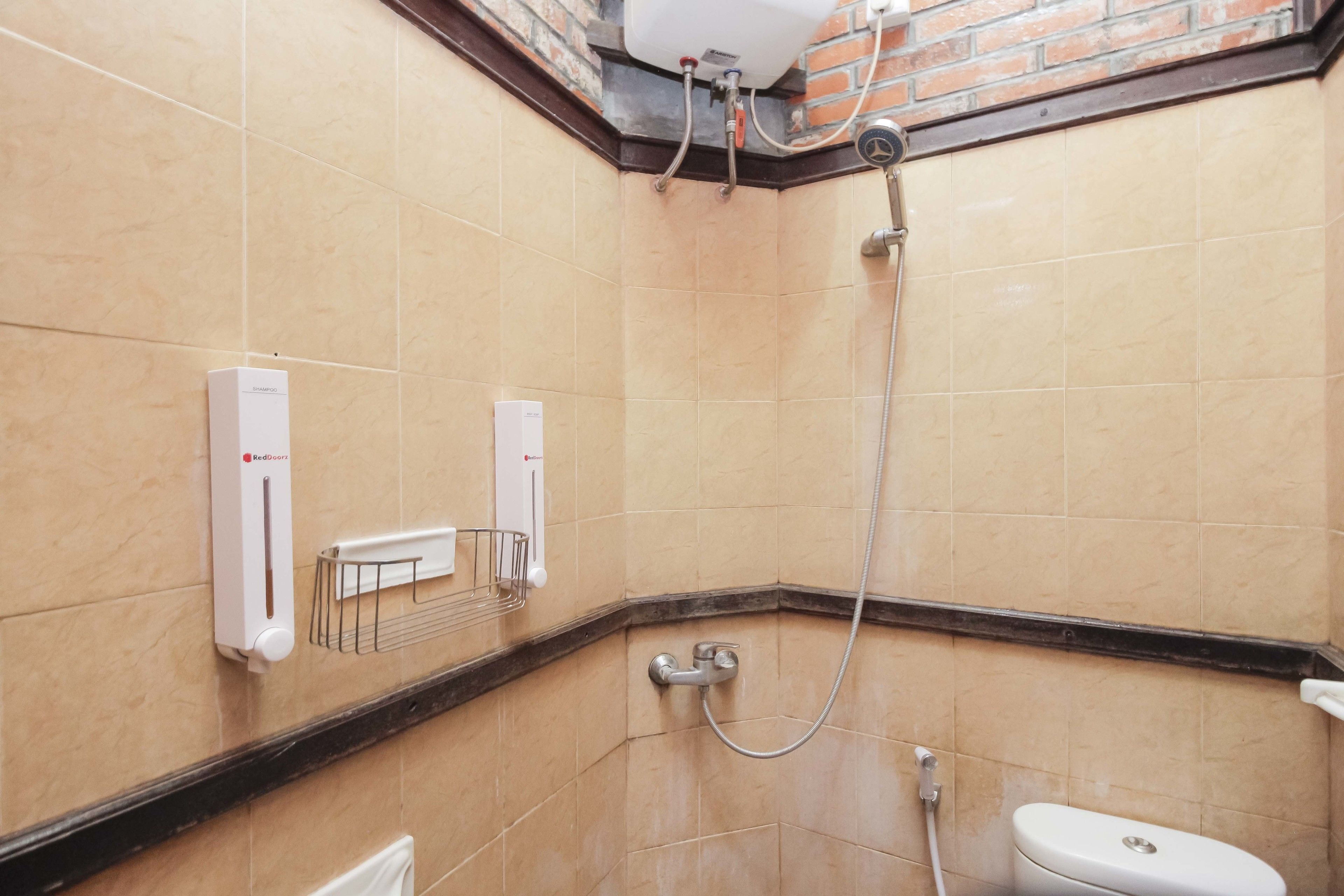 Ein Badezimmer mit beigen Fliesen, einer Dusche, einer Toilette und einem Heizkörper.