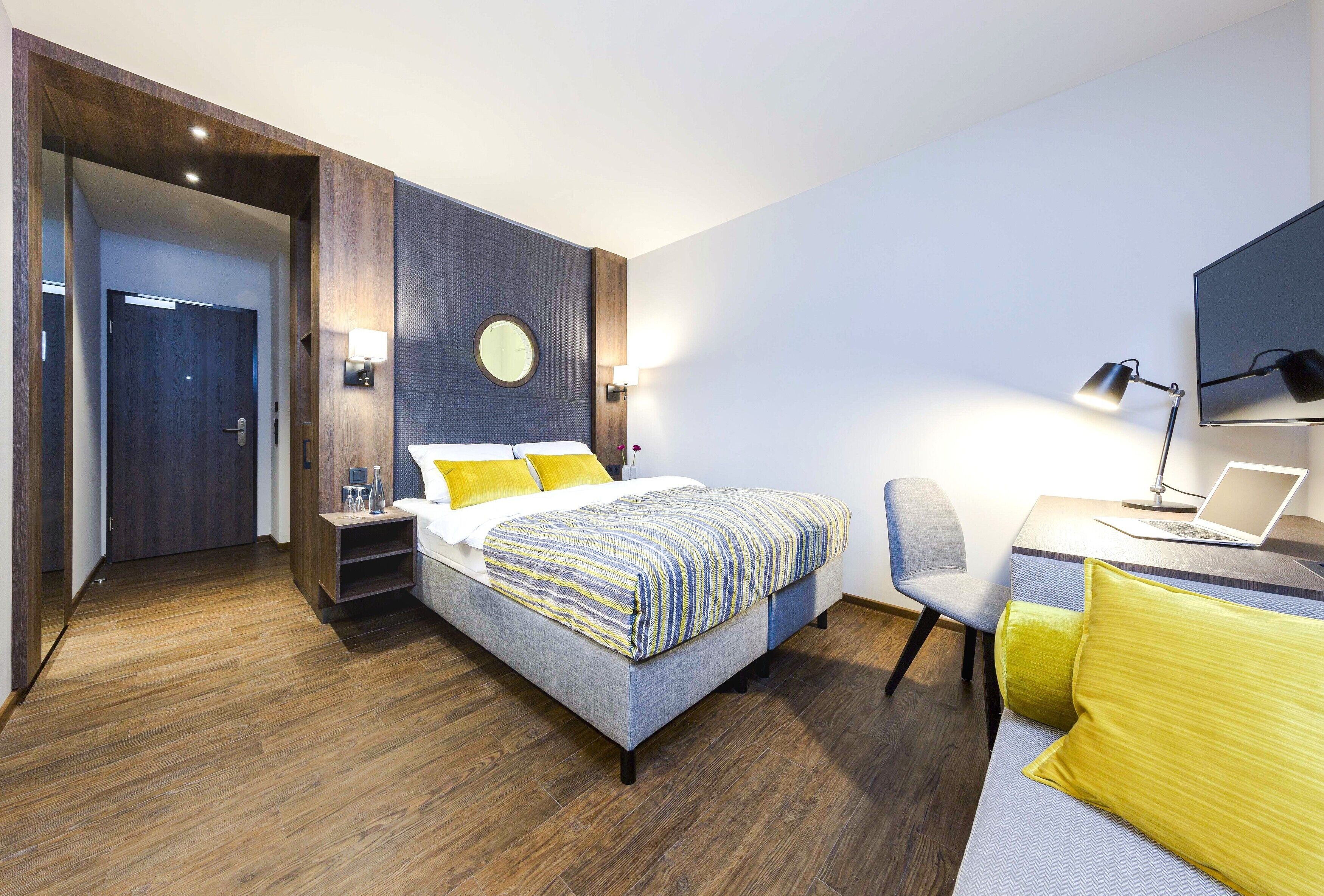 Una habitación de hotel moderna con cama, escritorio, silla y televisor.