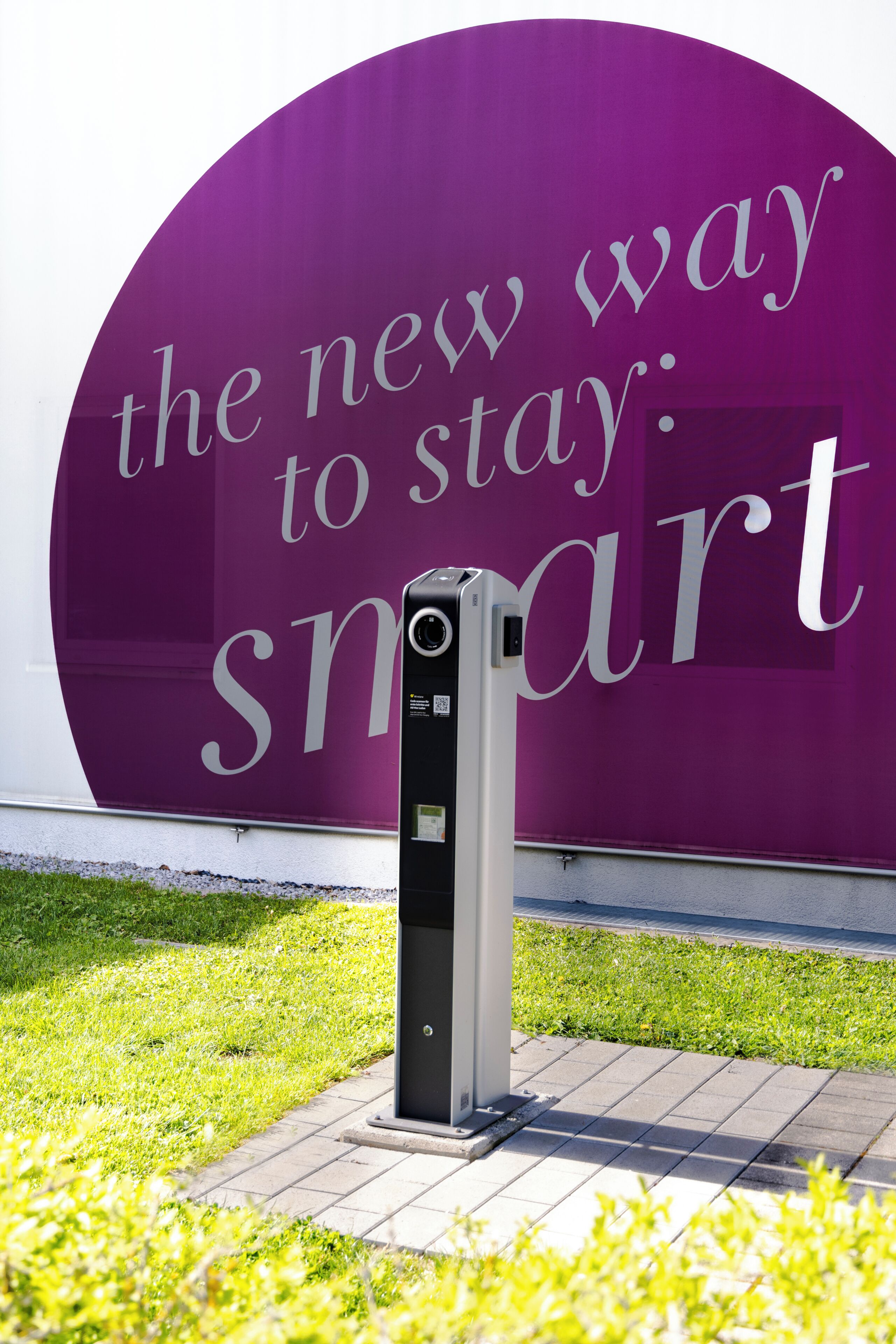 A large purple sign with the text 'the new way to stay: smart' and a modern, metallic device in front of it.