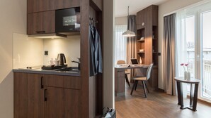 A modern kitchen with dark wood cabinets, a built-in microwave, and a coffee maker. There is a dining area with a laptop, a chair, and a small table with a vase of flowers. - Hotel Smartino (Schwäbisch Hall)