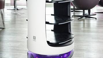 Ein weißer und schwarzer Elektroscooter mit Digitalanzeige, Ablagefläche und violetter Beleuchtung.