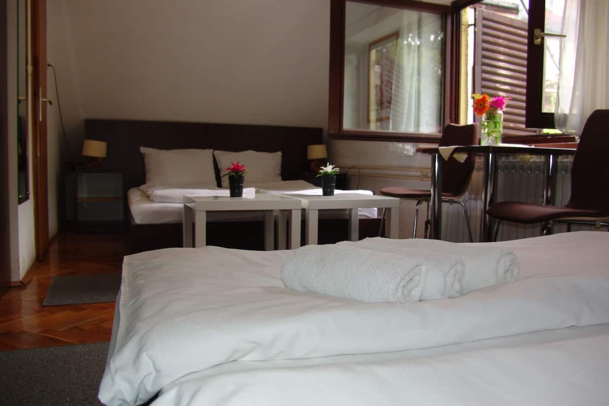 A hotel room with a bed, a desk, a chair, and a small table with two potted plants.