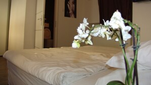 Ein ordentlich bezogenes Bett mit weißen Leinen in einem Zimmer mit Holzboden.