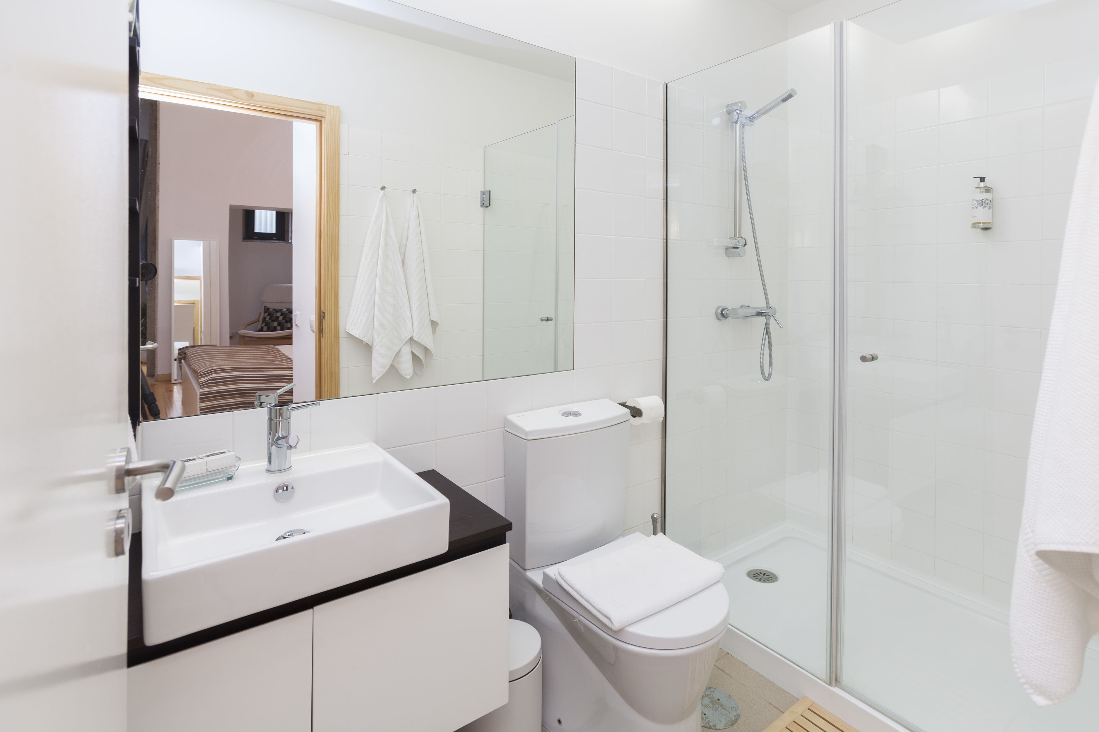 Een moderne badkamer met een douchecabine van glas, een witte wastafel en een toilet.