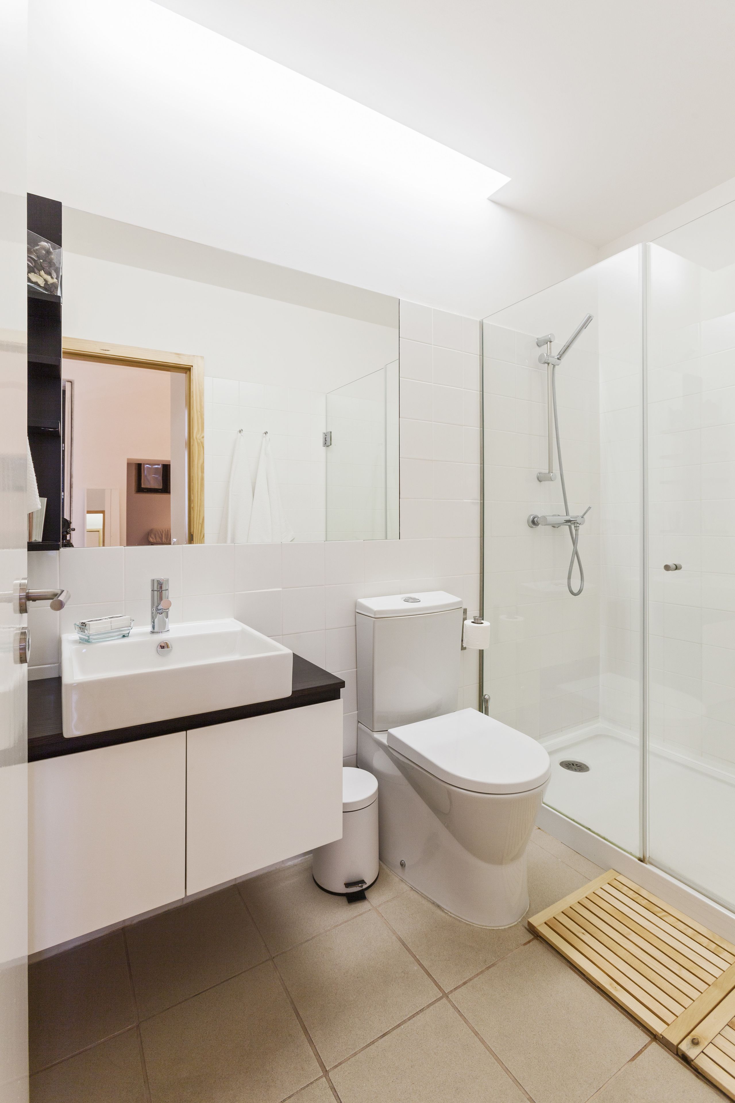 A modern bathroom with a white sink, toilet, and glass-enclosed shower.