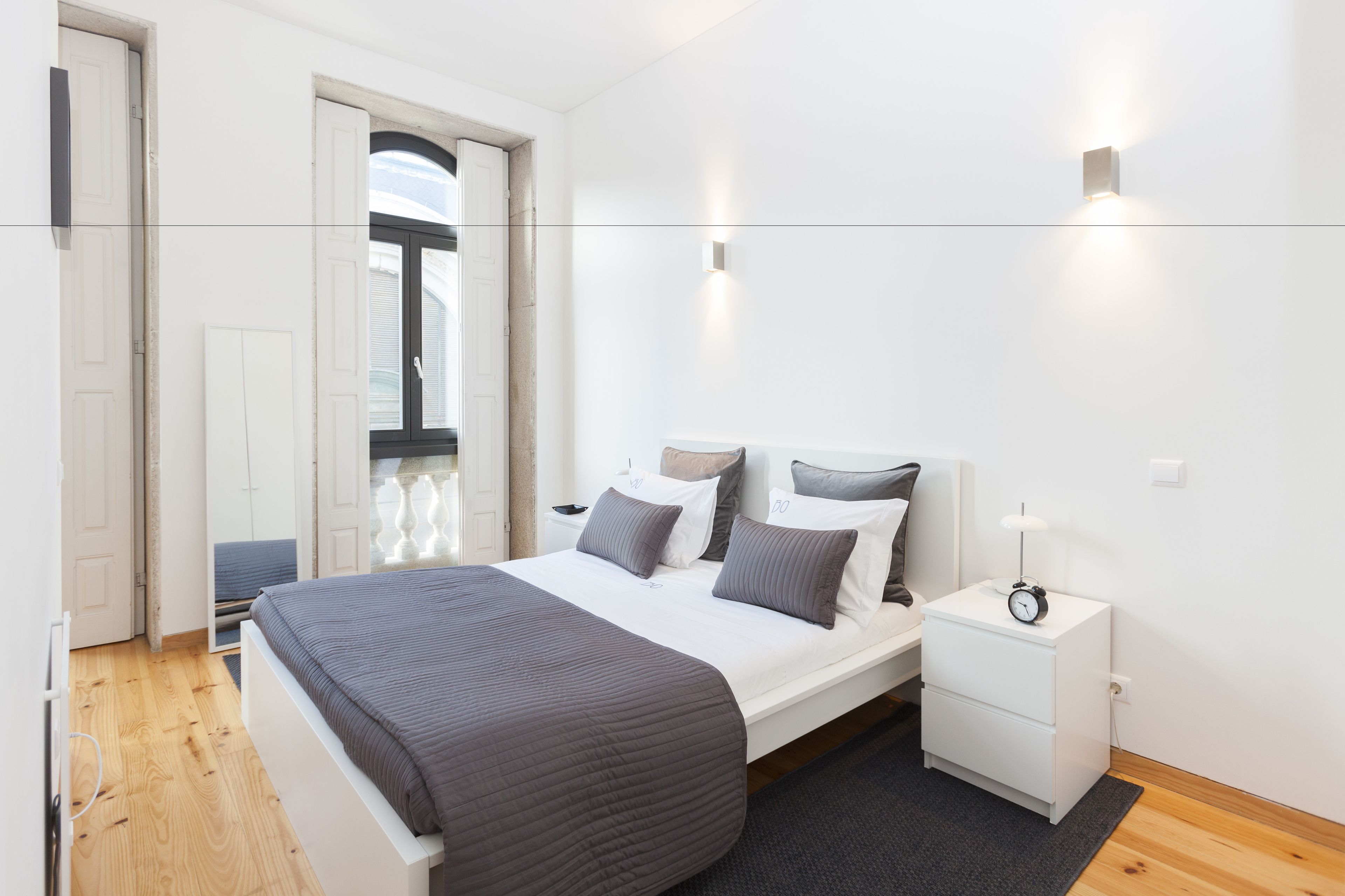 A modern bedroom with a large bed, bedside tables, and a window.