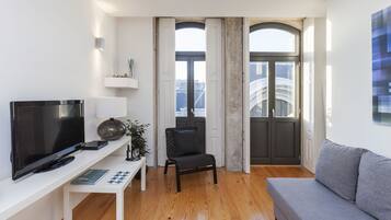 A modern living room with a flat-screen TV, a sofa, a chair, and a small table.