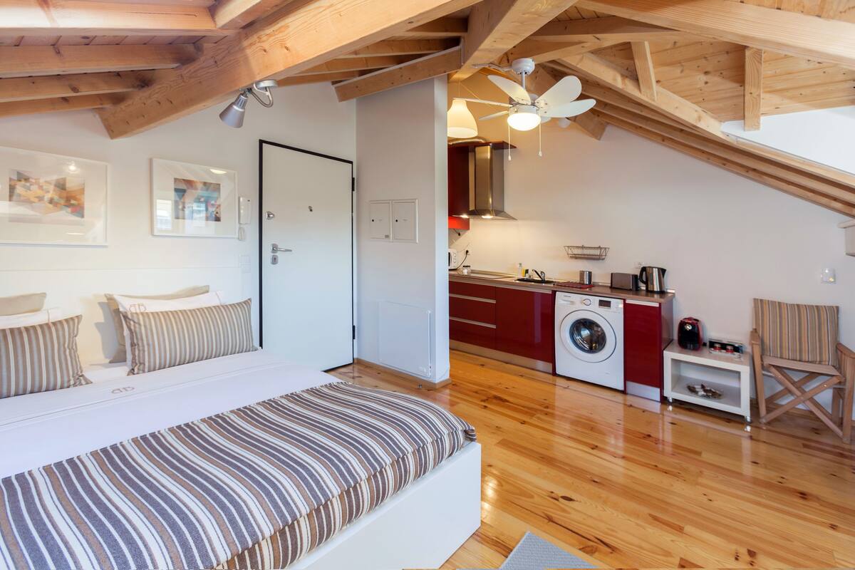 Une chambre avec un lit, un lave-linge et un coin cuisine.